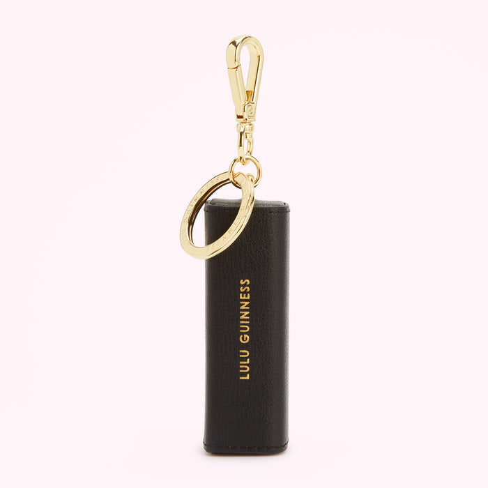 Black Lulu Guinness keyring with gold-tone hardware against a white background.