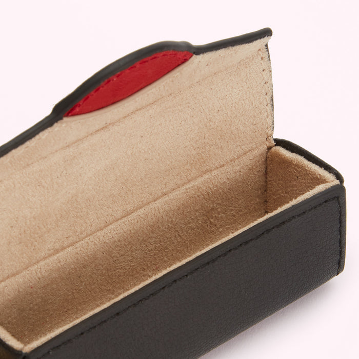 Black leather glasses case with beige suede interior and a red accent; open to show empty interior.