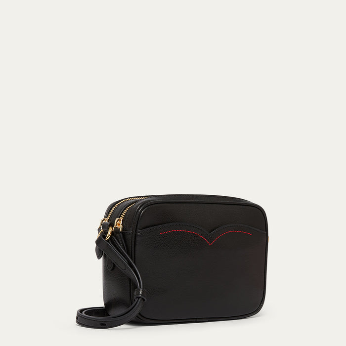 Black handbag with red stitching on a light grey background
