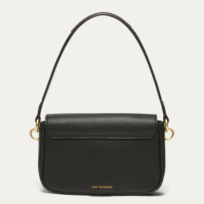 A black pebbled leather handbag by Lulu Guinness with a flap closure, gold-tone hardware, and a single shoulder strap, shown against a light off-white background.