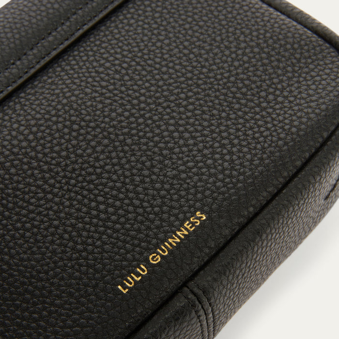 Close-up of a black pebbled leather handbag with gold foil 'LULU GUINNESS' branding on a white background.
