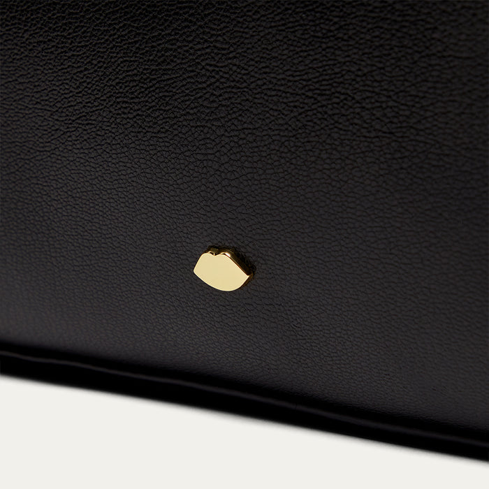 Close-up of a black leather product with a gold accent on a white background