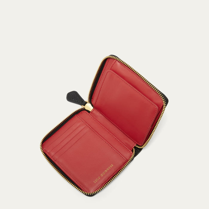 An open leather zip-around wallet with gold-tone hardware, red leather interior, photographed on a clean off-white background. The interior card slots and a small gold-tone brand stamp are visible.