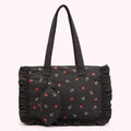 Black tote bag with ruffled edges and a repeating pattern of red lips and the Lulu Guinness logo. A smaller matching zippered pouch is attached to the bag.