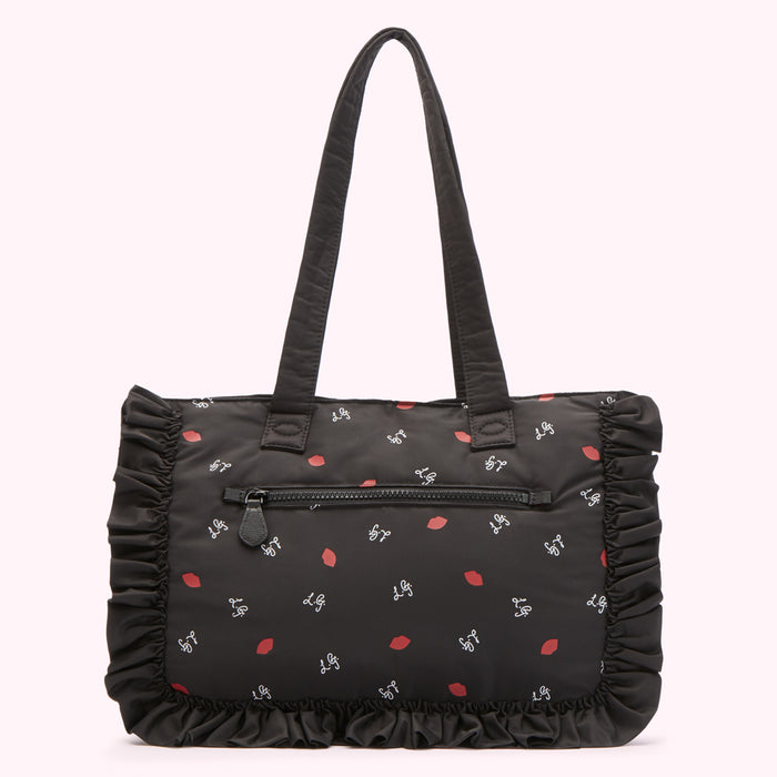 Black tote bag with ruffled trim and a lip print.