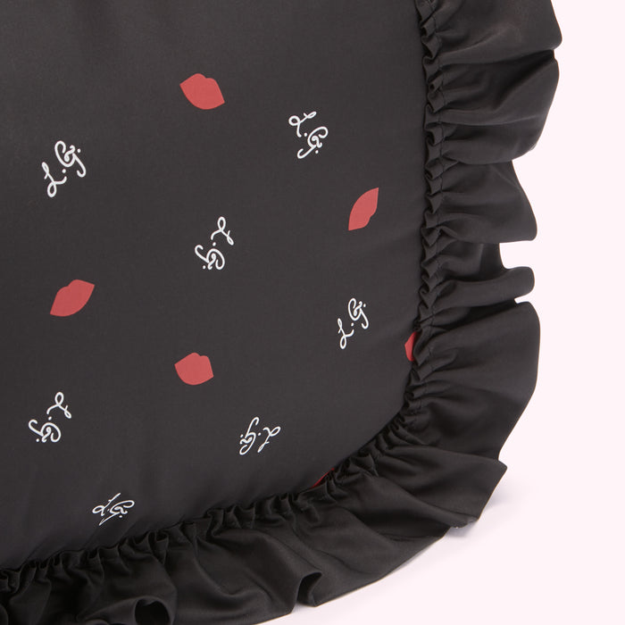 Black cushion with red lips and white script print, black ruffled trim.