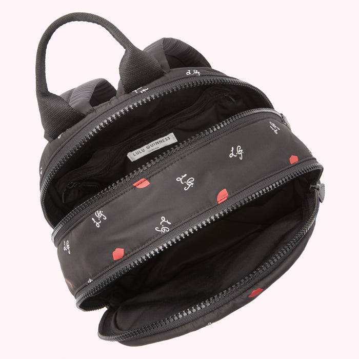 Open black Lulu Guinness backpack with red lips and logo print.