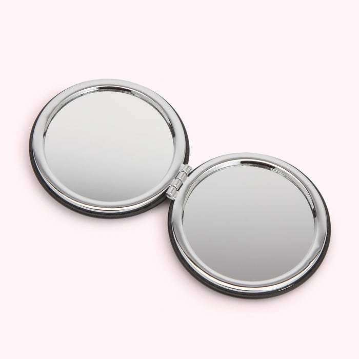 Compact mirror open, showing two round mirrors with black trim and silver frames.