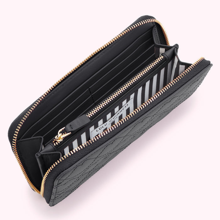 Open black quilted zip-around wallet by Lulu Guinness with gold zipper and black and white striped interior.