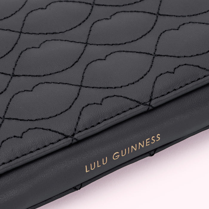 Close-up of a dark grey Lulu Guinness wallet with a quilted lip design.