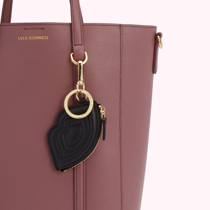 Close-up of a mauve Lulu Guinness tote bag with a black lip-shaped coin purse attached to it via a gold keyring.