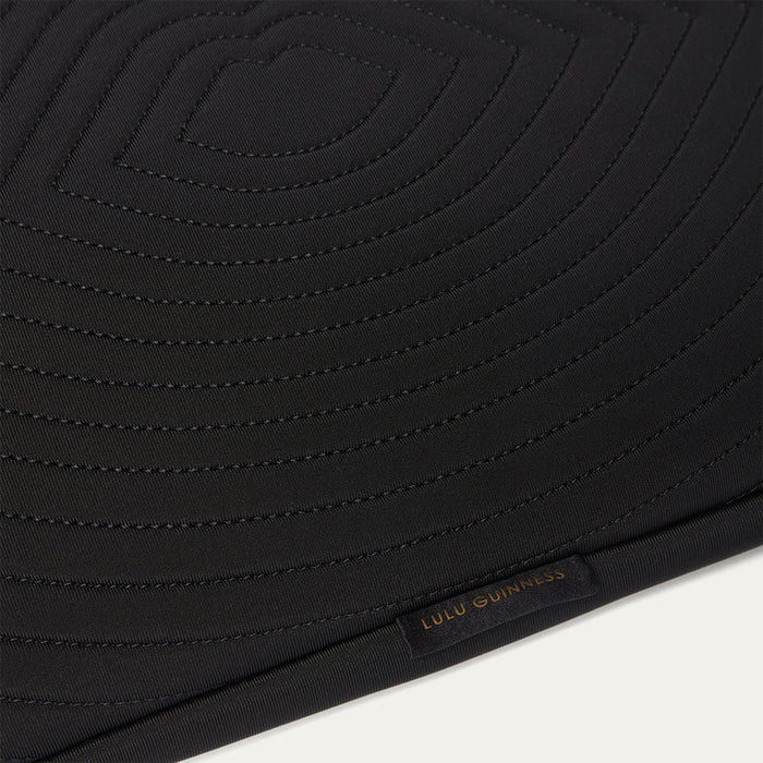 Close-up of a black laptop sleeve with quilted details and 'Lulu Guinness' branding on a white background
