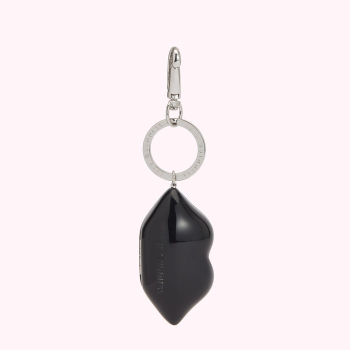 Black lip-shaped keychain with silver ring and clasp. Lulu Guinness branding is visible.