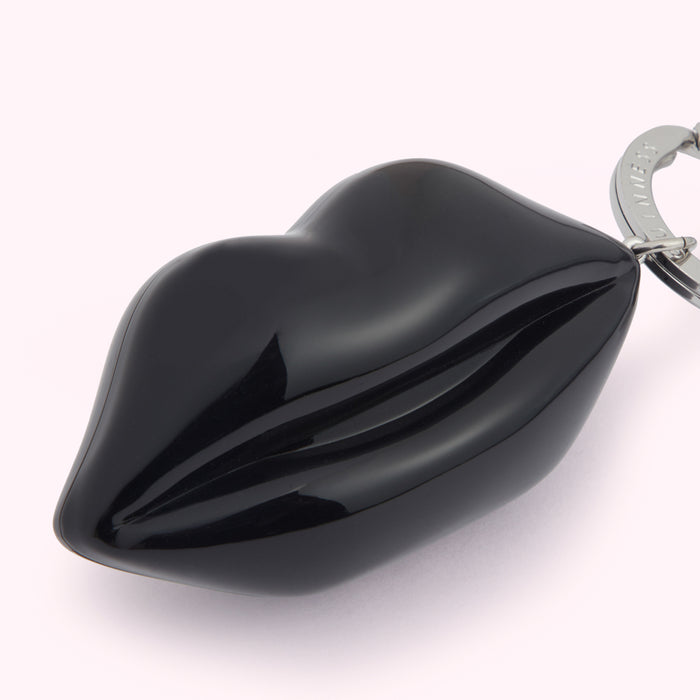 Close-up of a black lip-shaped keychain on a white background.
