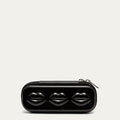 Black sunglasses case with lip details and silver zips on a grey background.