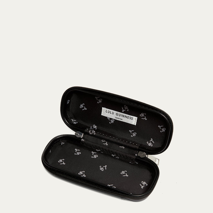 Black sunglasses case open to reveal a Lulu Guinness printed lining on a grey background.