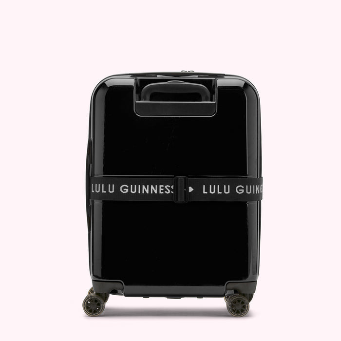 Black Lulu Guinness suitcase with a luggage strap.