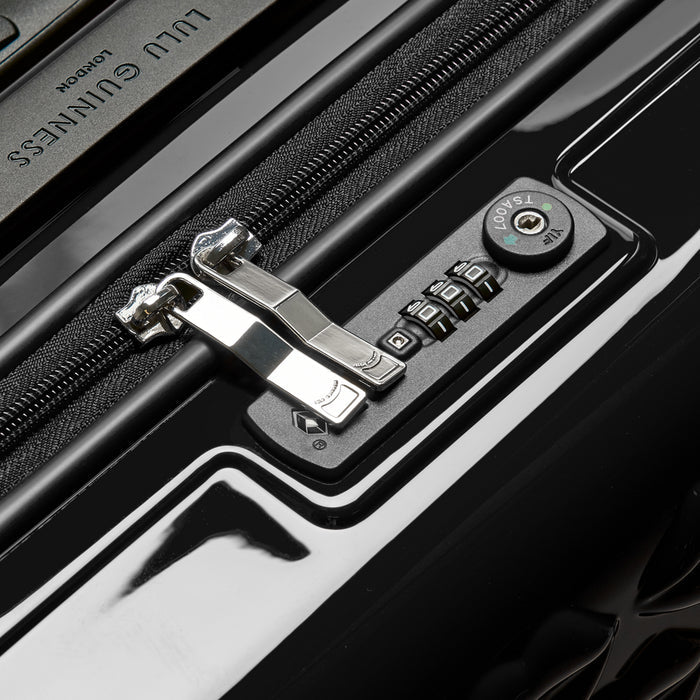 Close-up of a black suitcase's TSA-approved combination lock and zipper. The luggage features the Lulu Guinness London logo.