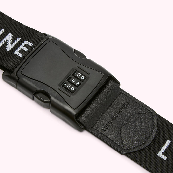 Close-up of a black luggage strap with a built-in combination lock. The strap features the "Lulu Guinness" branding.