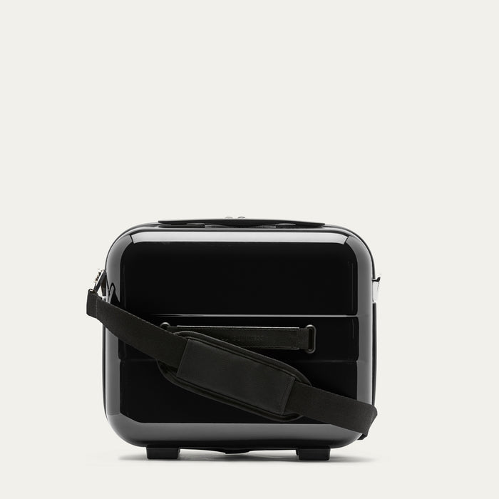 Black vanity case with a shoulder strap on a light gray background
