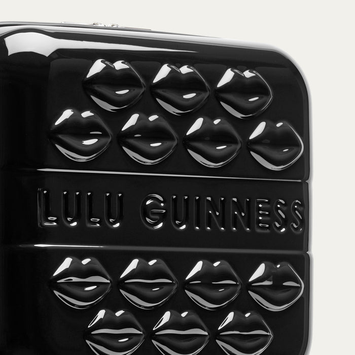 Close up of a black vanity case with lips and 'Lulu Guinness' branding on a white background