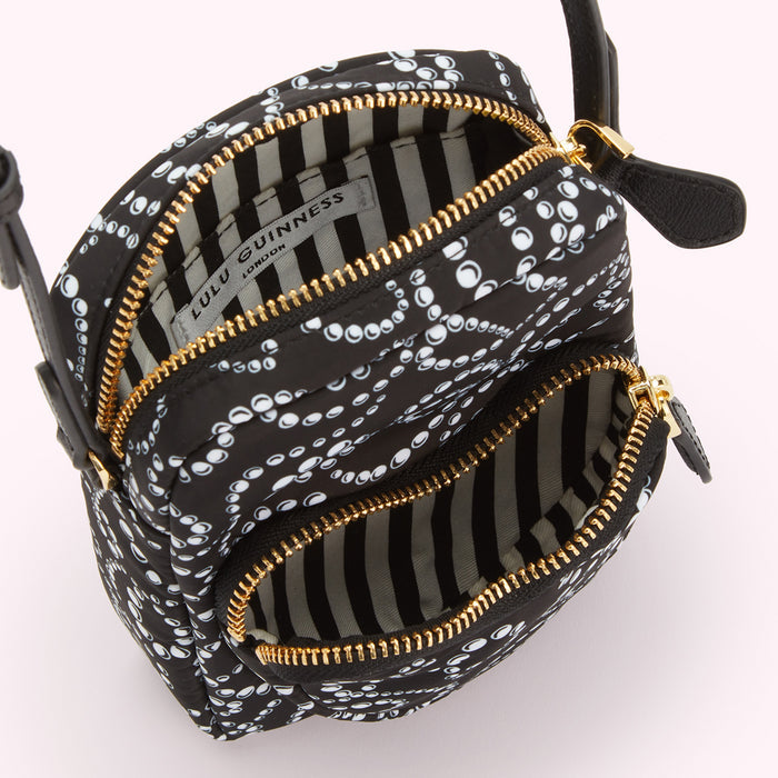 Black Lulu Guinness crossbody bag with white pearl pattern, gold zippers, and black and white striped interior.