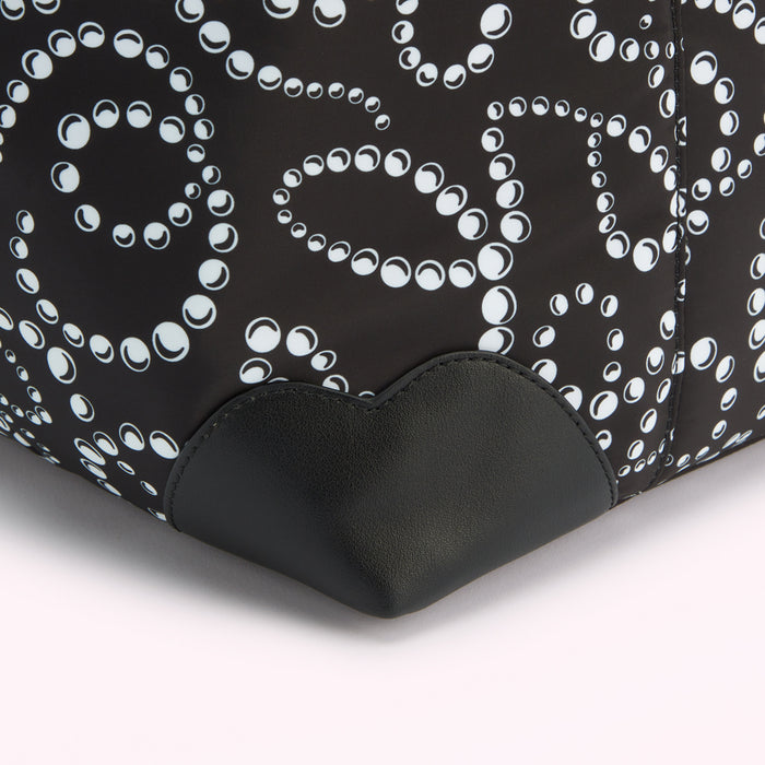 Close-up of a black bag with a white pearl pattern and black leather bottom.