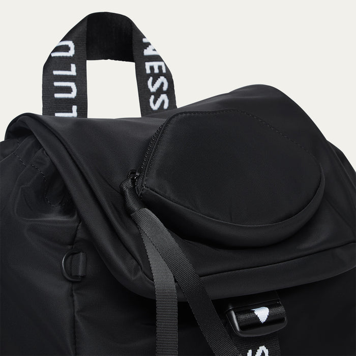 Black backpack with visible branding and a lip-shaped pocket on a light grey background