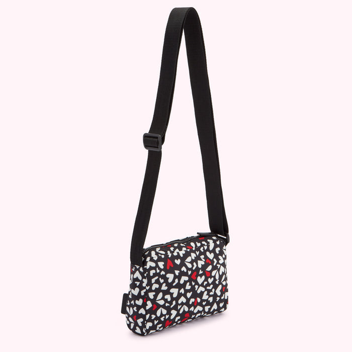 Black crossbody bag with a white and red heart pattern.