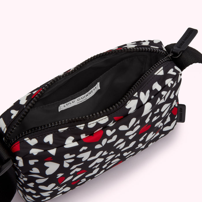 Black crossbody bag with a white and red heart pattern.