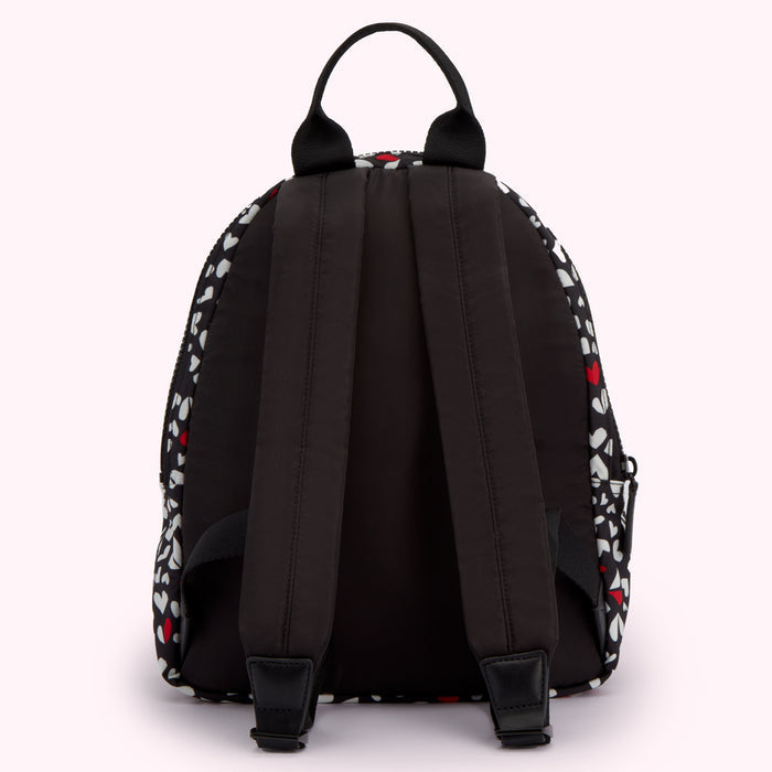 Black backpack with white and red heart pattern, viewed from the back.
