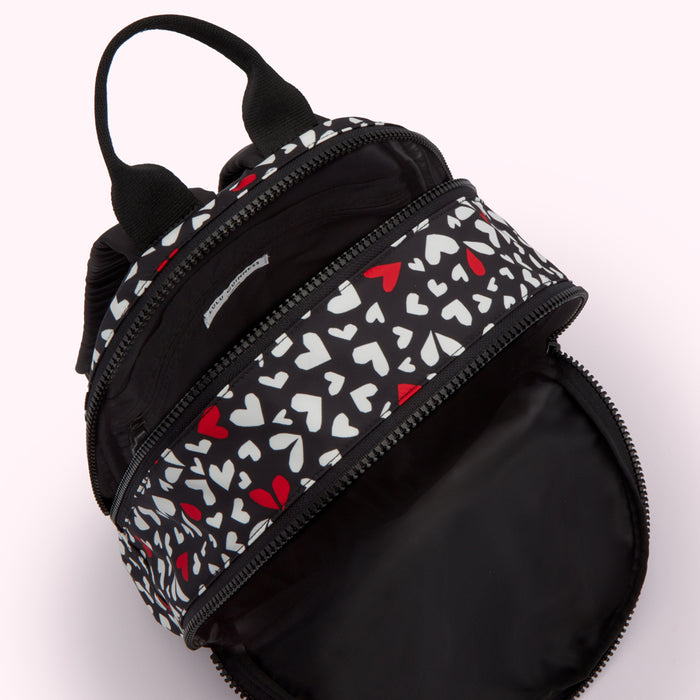 Black backpack with white and red hearts pattern, open to show the inside.