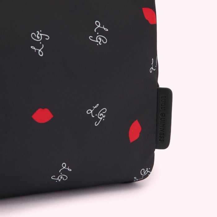 Close-up of a black Lulu Guinness makeup bag with a red lips and L.G. logo print.