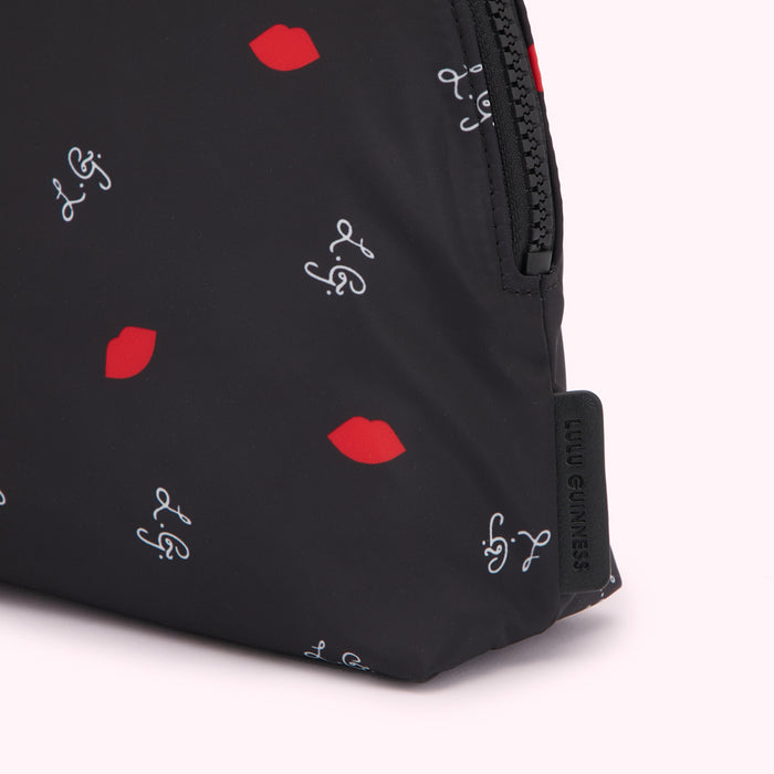 Close-up of a black Lulu Guinness makeup bag with a red lips and script logo print.