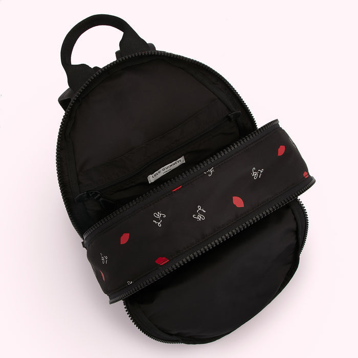 Black Lulu Guinness backpack open to reveal a red lips and logo print lining.