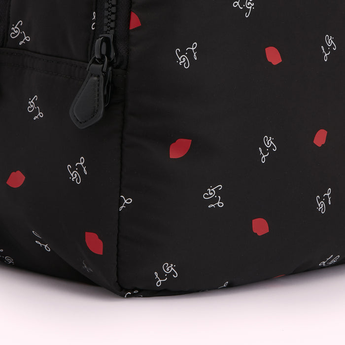 Close-up of a black backpack with a red lips and cursive writing pattern.
