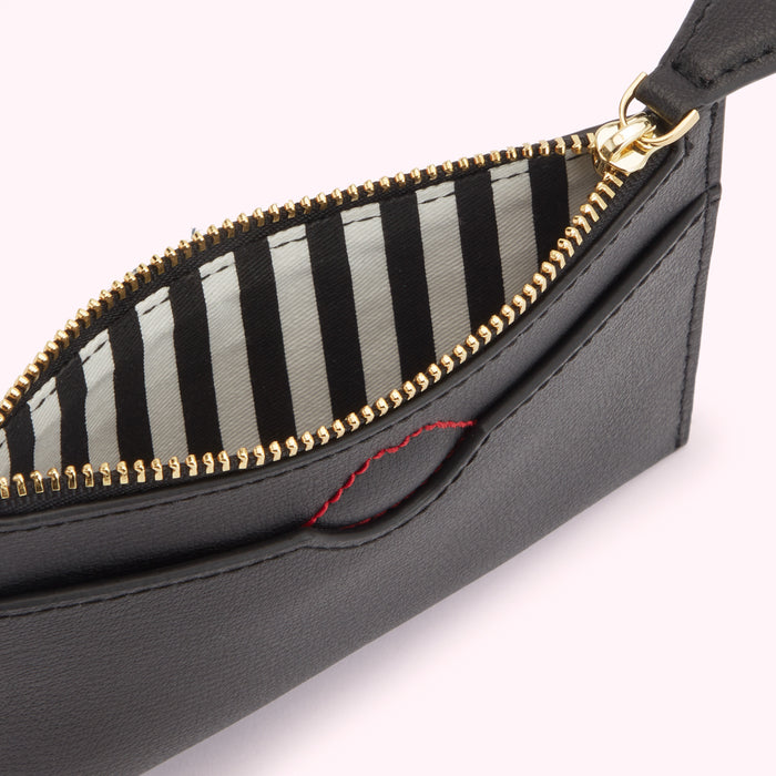 Close-up of a black leather zip-around pouch with a black and white striped interior and a small red detail.