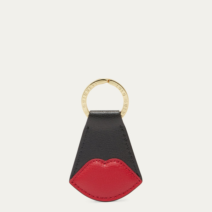 Black and red lip-shaped keychain with a gold ring on a white background