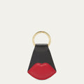 Black and red lip-shaped keychain with a gold ring on a white background