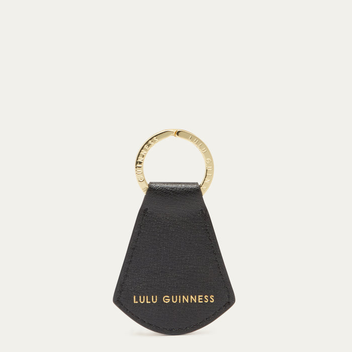 Black leather key fob with gold ring and 'Lulu Guinness' branding on a white background