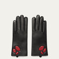 Pair of black leather gloves with red lip designs on a light gray background