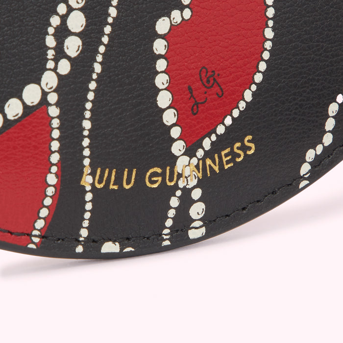 Close-up of a Lulu Guinness cardholder featuring a black background with red heart shapes outlined in white pearls and gold lettering.