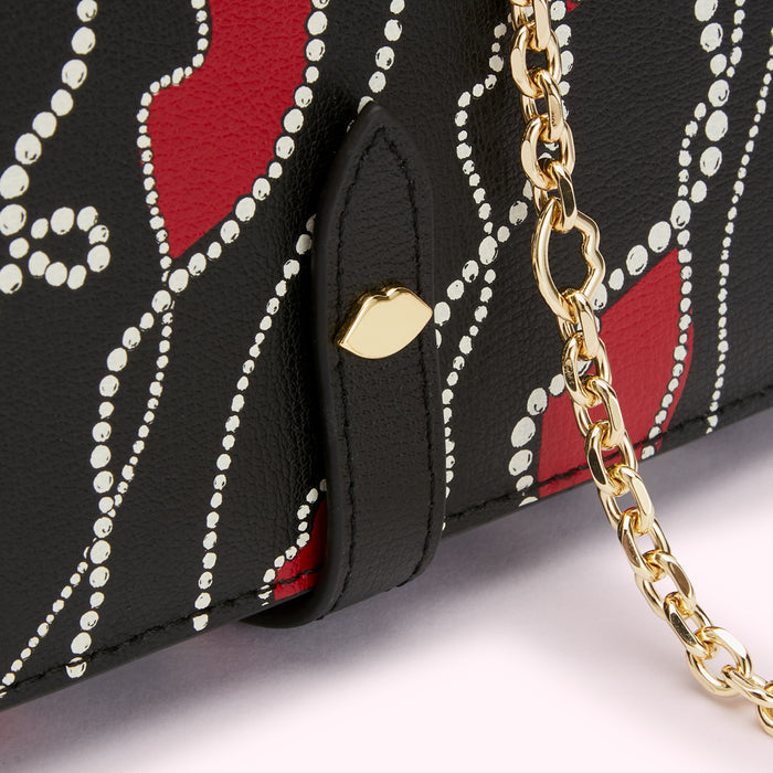 Close-up of a black wallet with a red and white lip print, gold chain, and clasp.