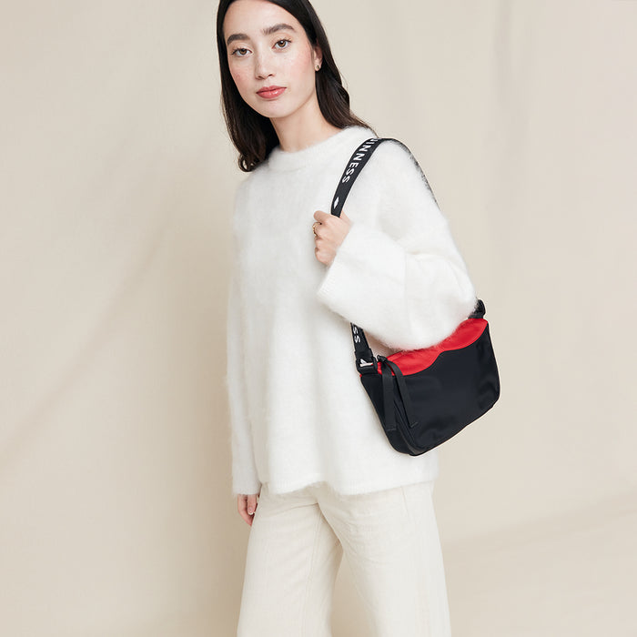 Woman holding a black and red bag against a beige background