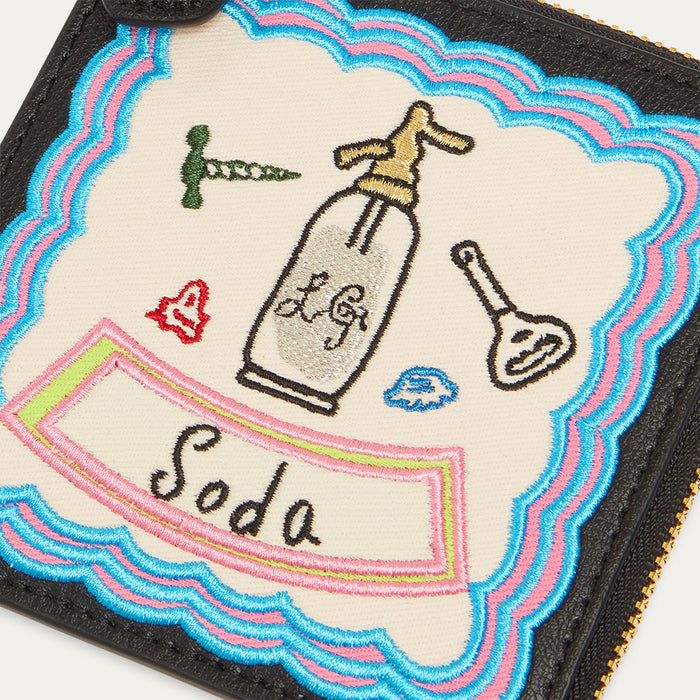 Embroidered coin purse with a bottle labelled 'Soda' and various icons on a colourful border.
