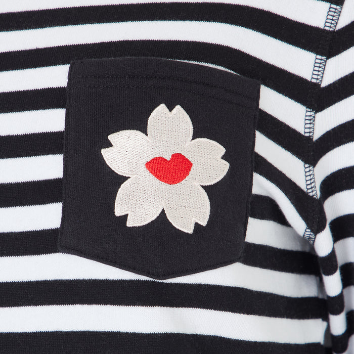 Close-up of a black and white striped shirt pocket with an embroidered cherry blossom featuring a red lip print in the centre.