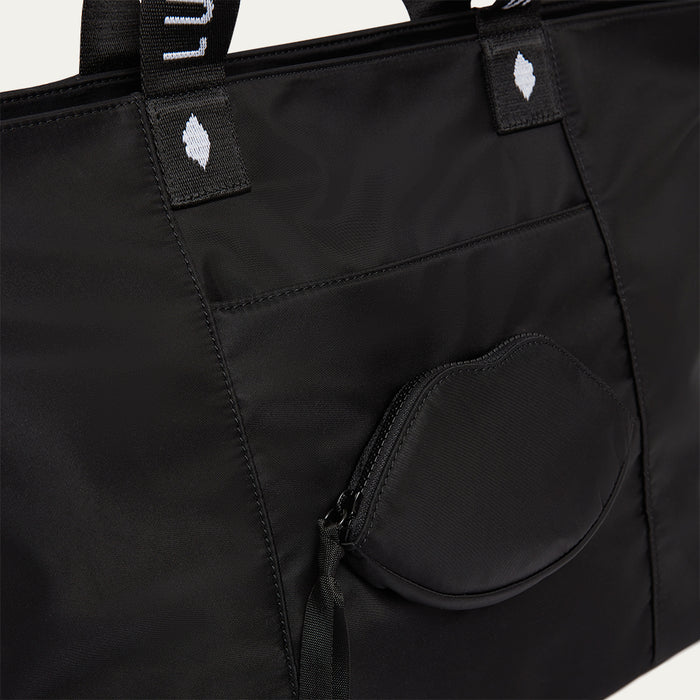 Black tote bag with a lip-shaped pocket and visible brand logo on a white background