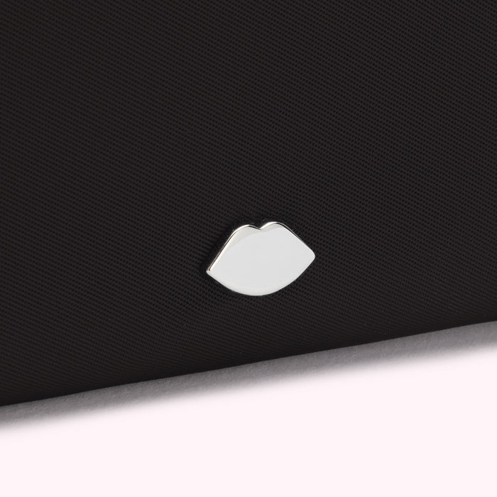 Close-up of a black textured surface with a silver lip-shaped emblem.
