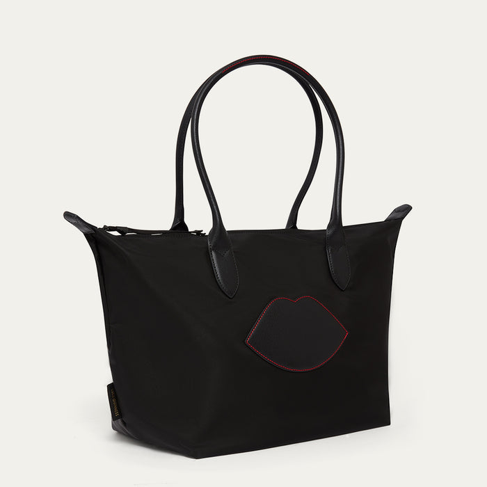 Black tote bag with red lip design on a light grey background