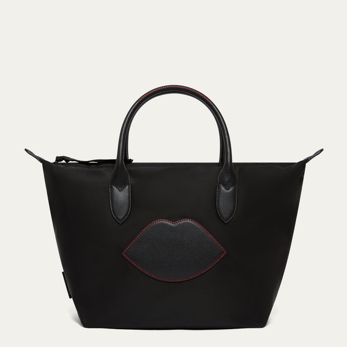 Black handbag with a lip-shaped patch on a light gray background